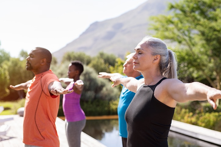 A group of adults doing a yoga pose outside in front of a mountain