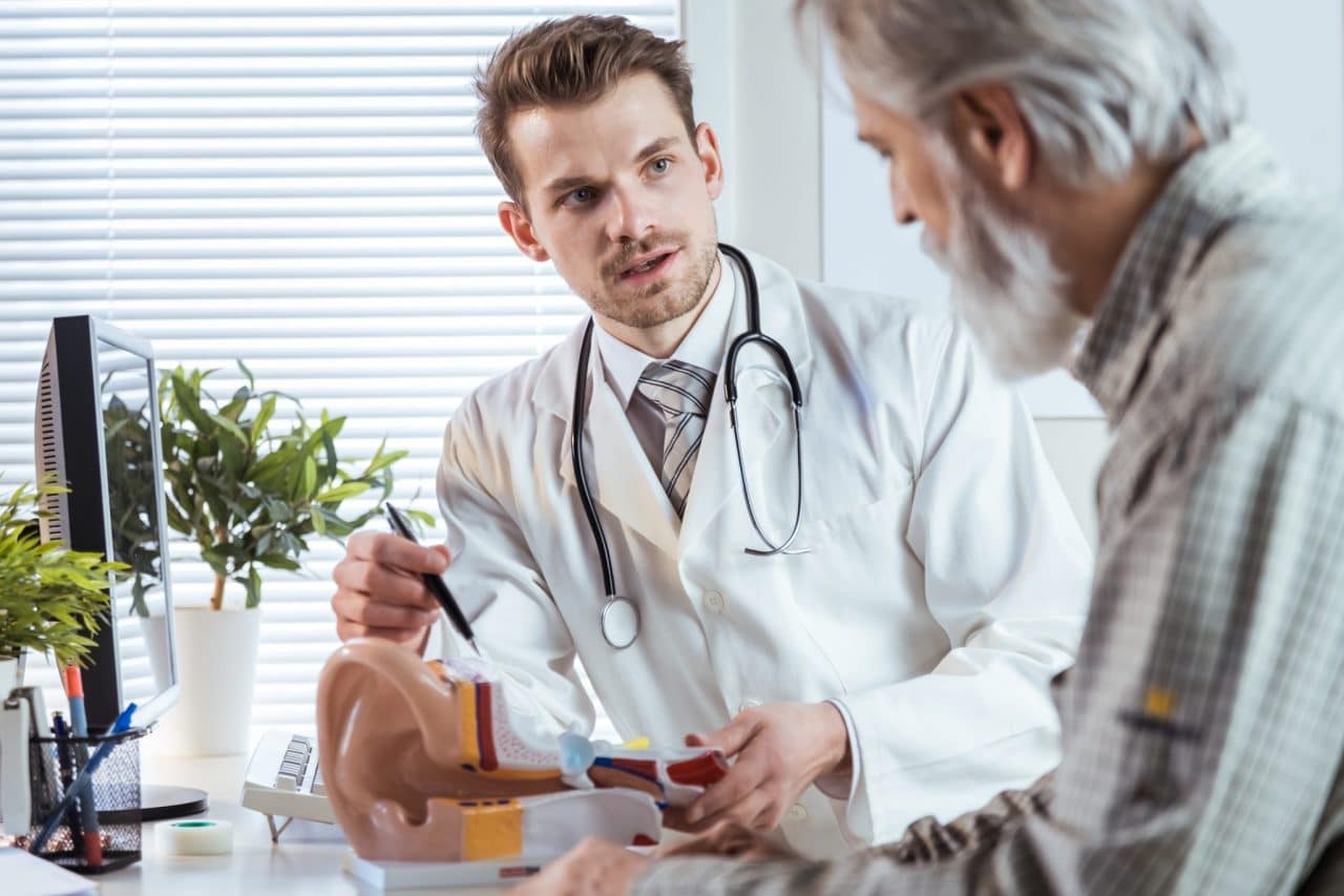 An audiologist showing a diagram of the ear to a patient
