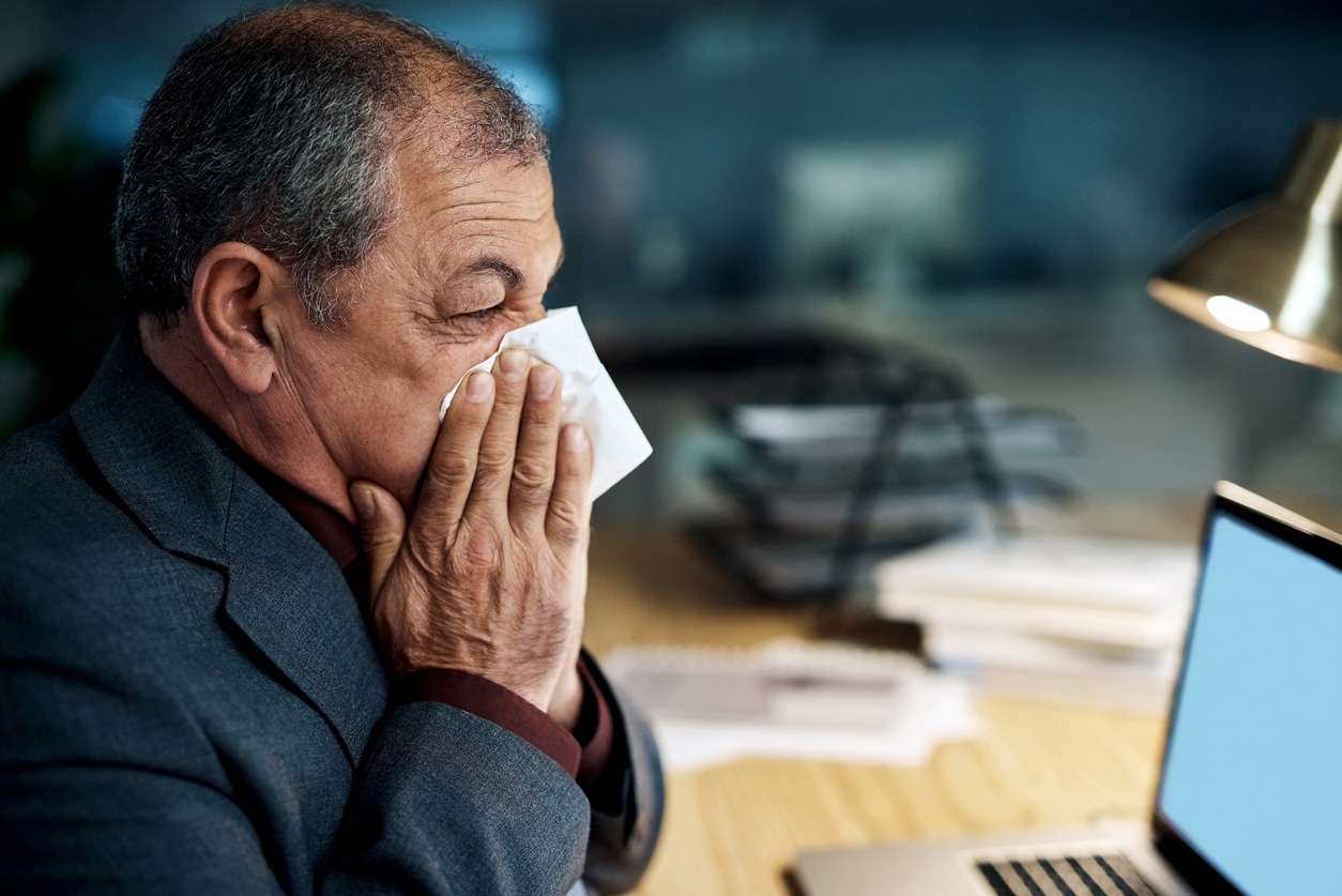 A person blowing their nose at a desk