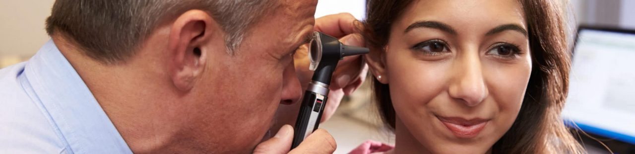 A health care provider inspecting a patient with an otoscope