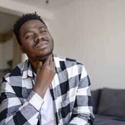 Man with sore throat holds throat