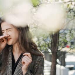 Woman sneezing near the trees