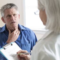 Man with a sore throat talks to his doctor