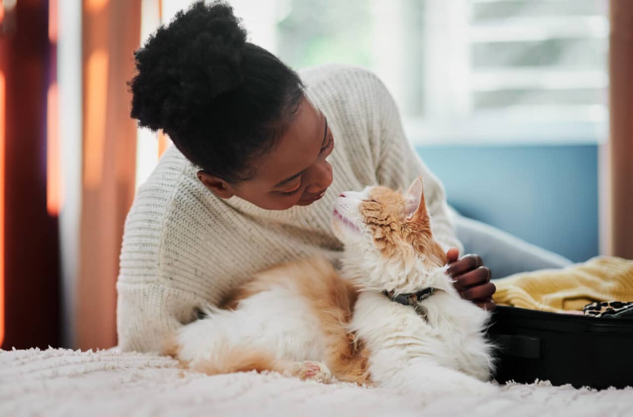 Happy woman in her apartment snuggling with her beautiful orange and white longhaired cat.