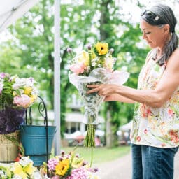 Woman at a farmers market purchasing fresh flowers for her home.