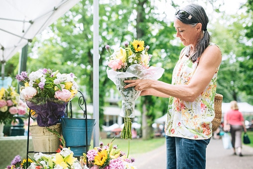 Woman at a farmers market purchasing fresh flowers for her home. 