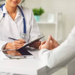 Allergist takes notes during an initial consultation with a patient.