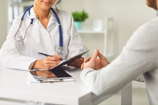 Allergist takes notes during an initial consultation with a patient.